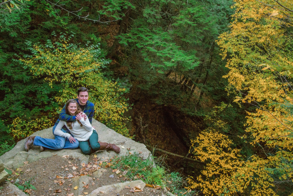 couple sits on rock on the edge of a cliff in mcconnells mills park