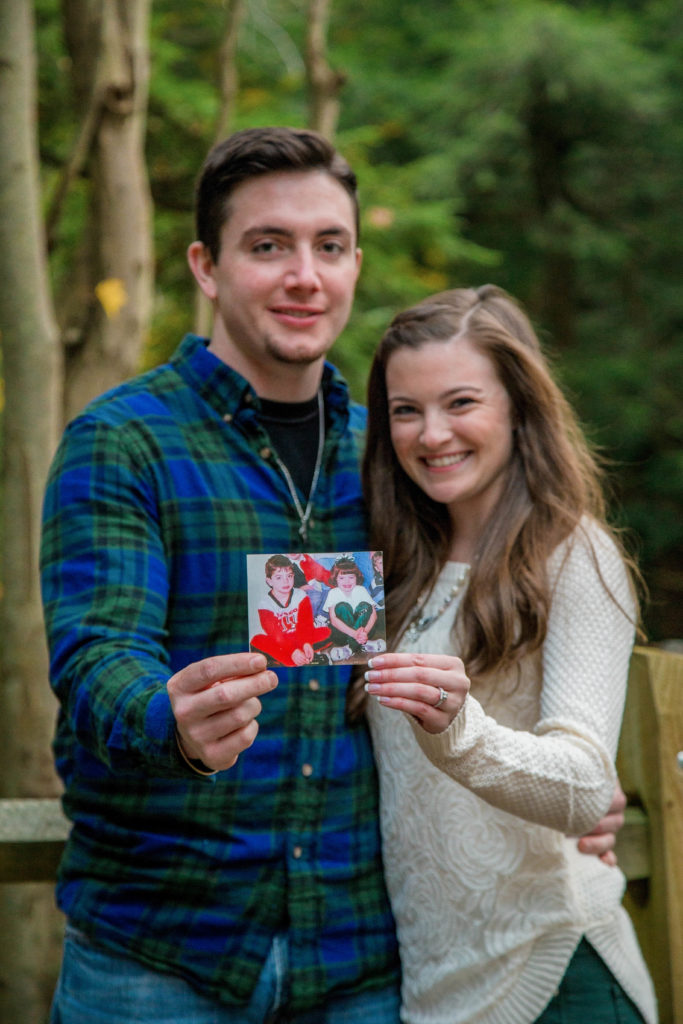engaged couple holds up photo of themselves as children