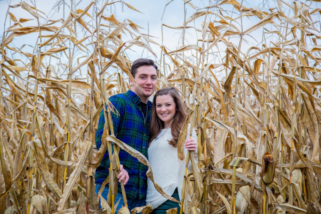 engaged couple stands in corn field