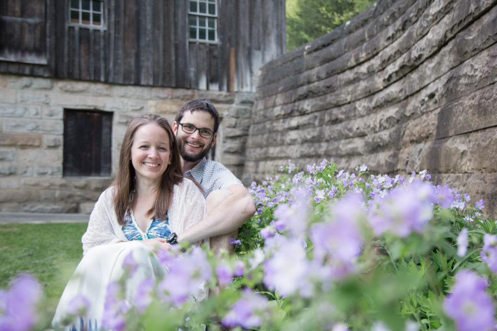 couple sits in front of barn on a bench