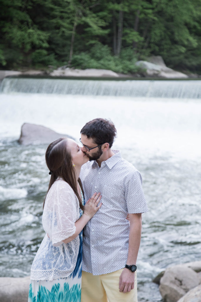 couple stands in front of waterfall and kisses
