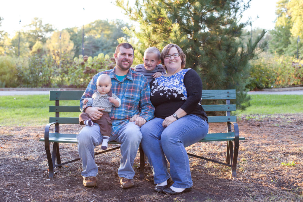 family sits on park bench in highland park