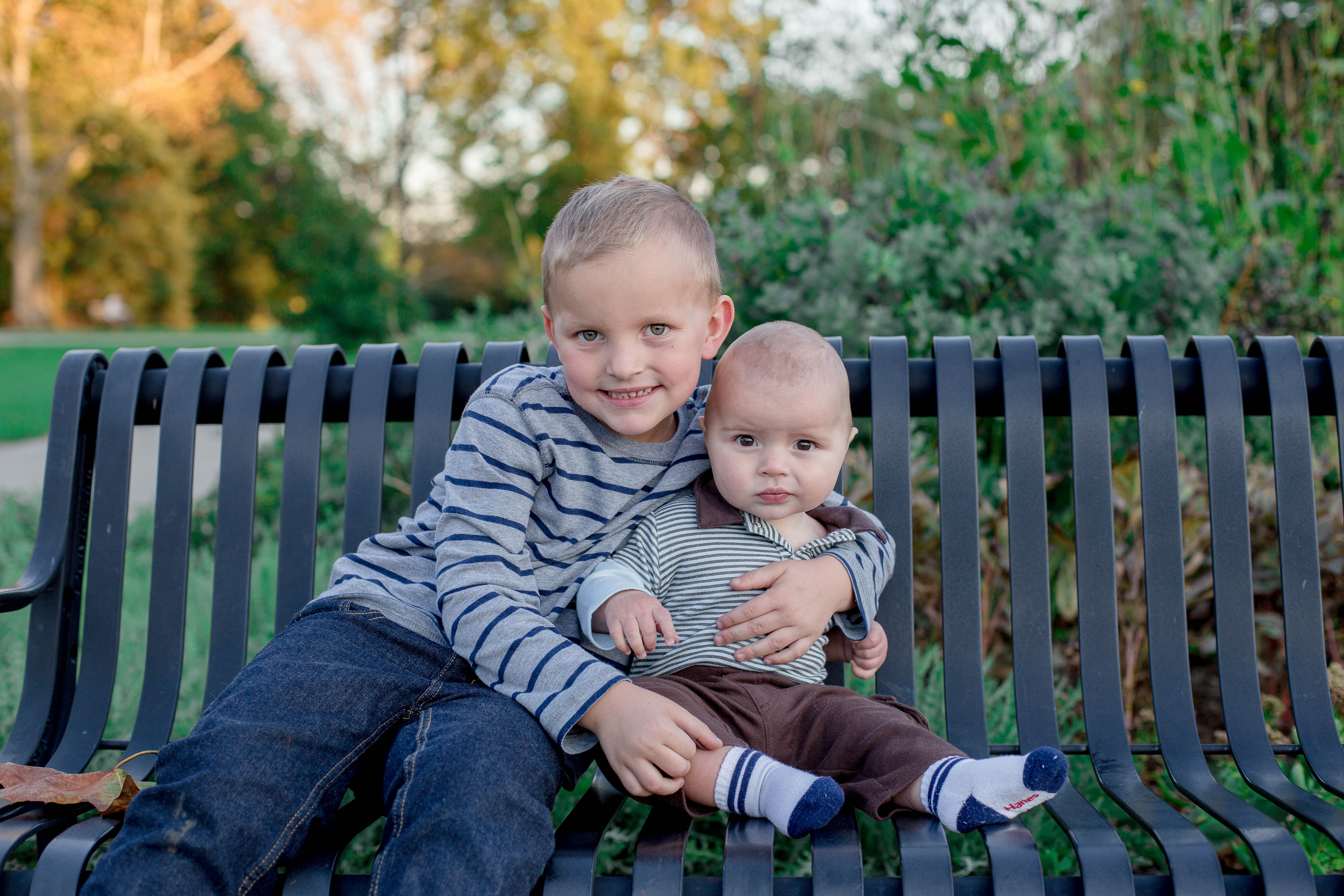 brothers snuggle on a bench in higland park in the fall