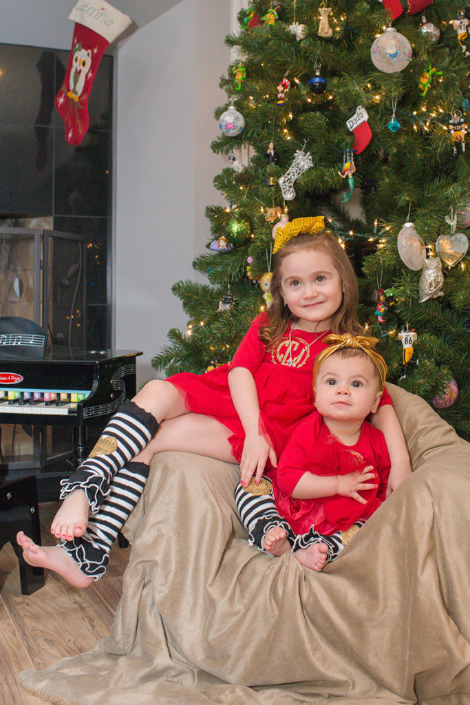 sisters lounge in a chair in front of the christmas tree