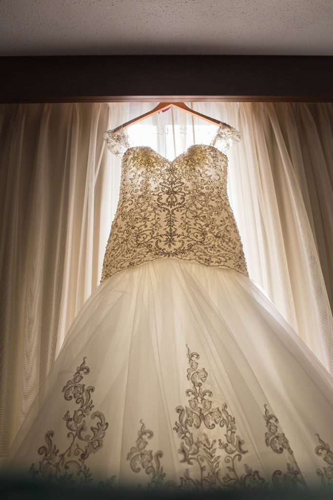wedding dress hangs in window of hotel room