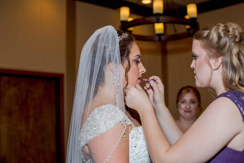 bridesmaid re-applies bride's lipstick before ceremony