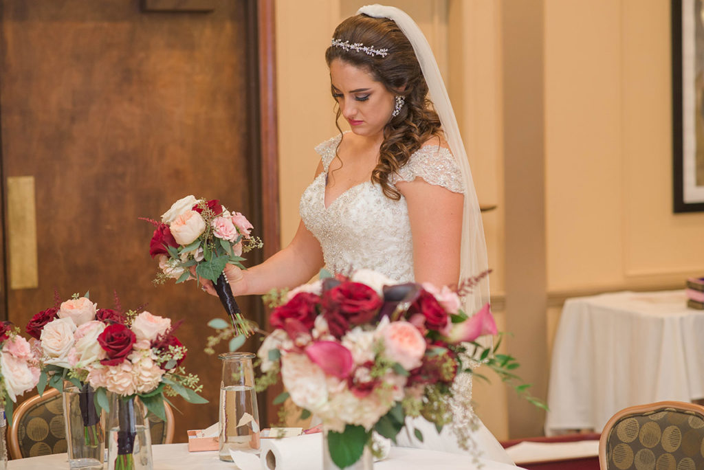 bride checks out bouquets of pink, burgundy and white flowers