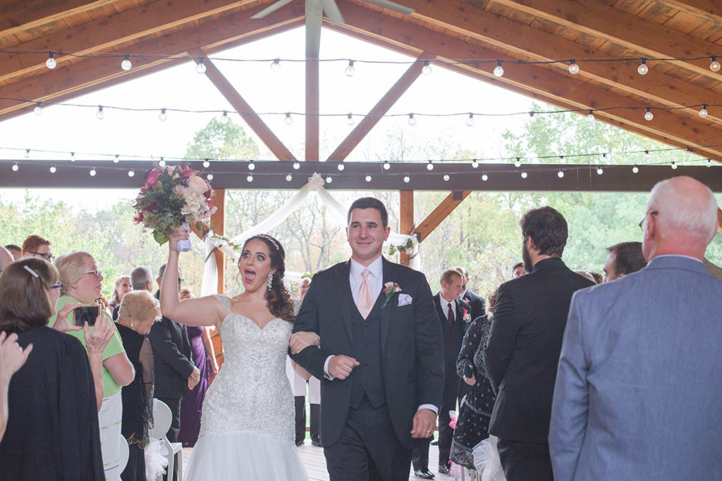 bride and groom cheer as they walk up the aisle after being married