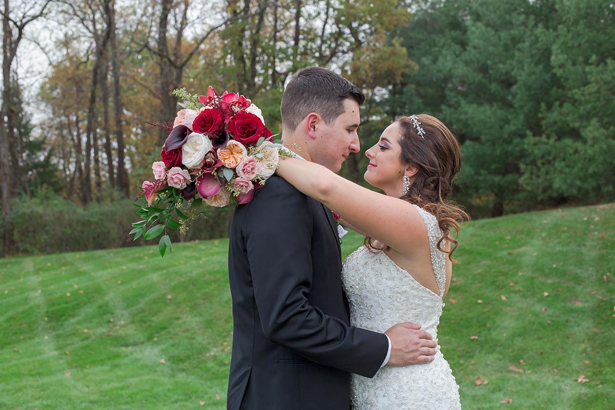 bride wraps arms around groom's soulders while holding bouquet