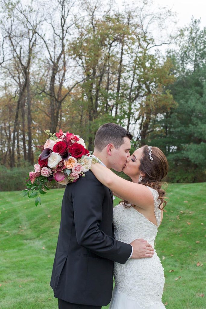 bride and groom wrap arms around each other and kiss