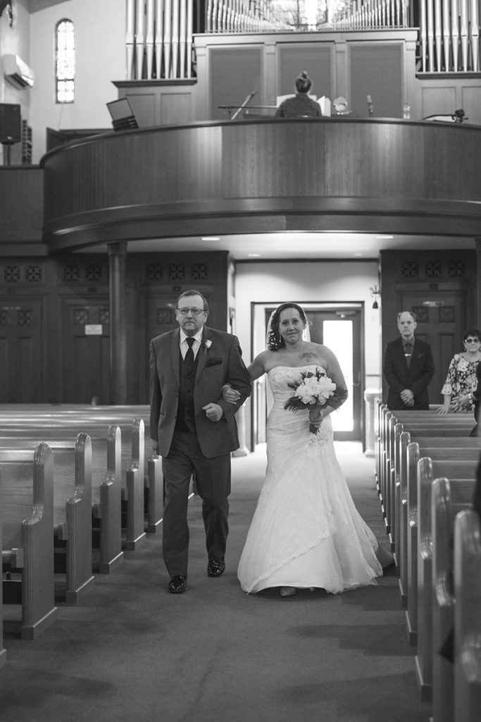 bride and her father walk down the aisle of church