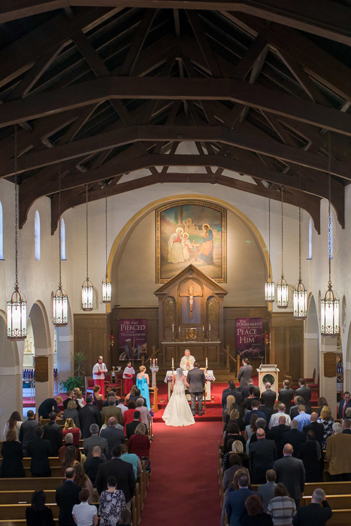 view of bride and groom standing at altar from balcony of church