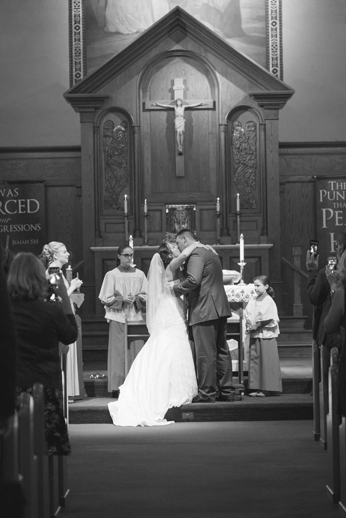 bride and groom share their first kiss during wedding ceremony