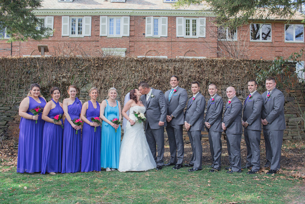 bridal party lines up in front of stone wall at robin hill park in moon township