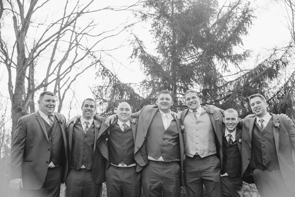 groom and groomsmen stand with arms around each other
