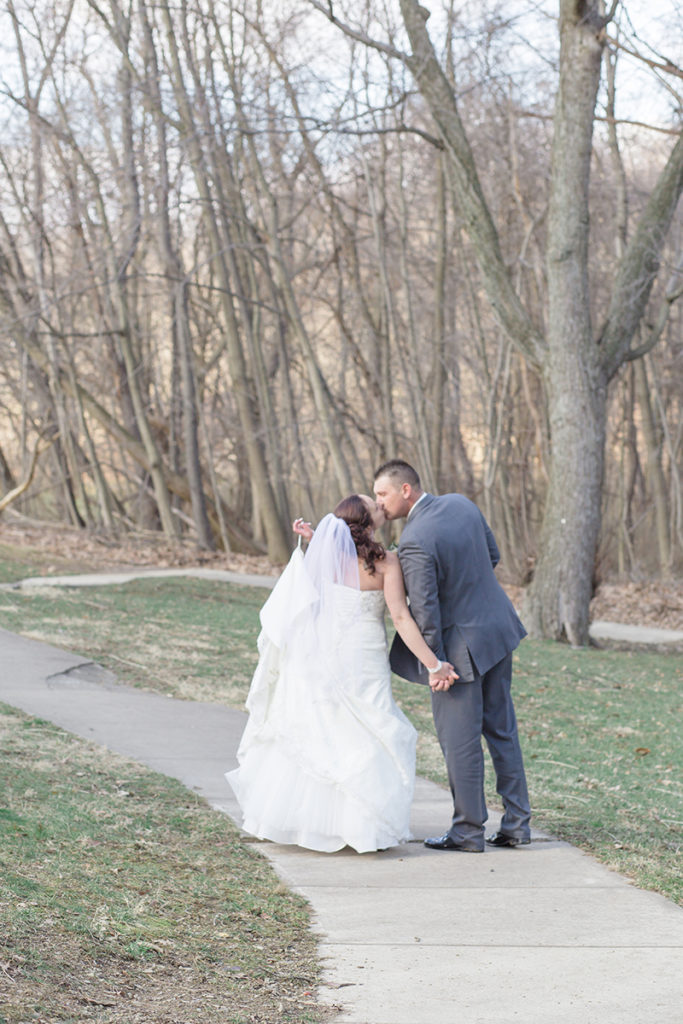 bride and groom pause from walking down sidewalk to kiss