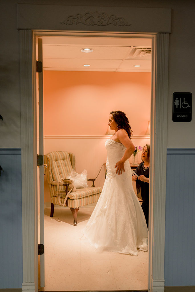 bride looks in mirror as her mother laces up her wedding dress