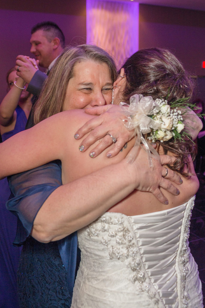 bride gives her mom a hug as they dance 