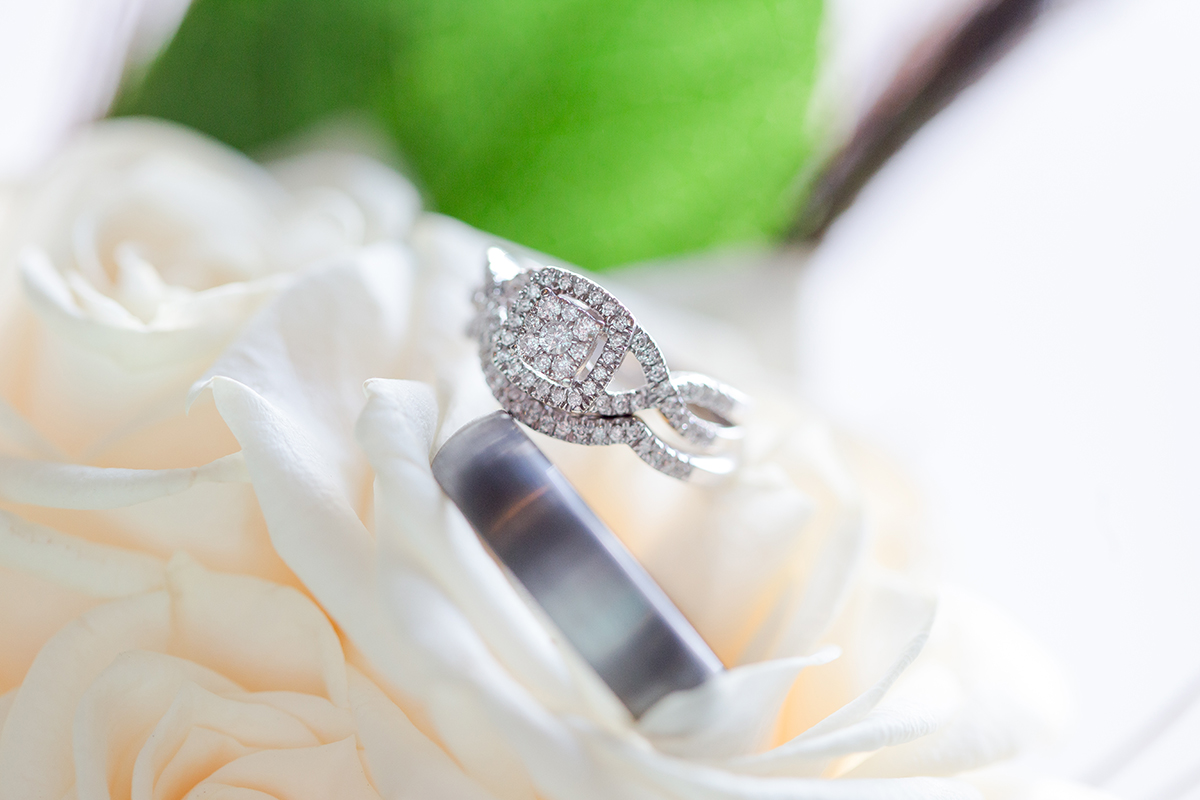 wedding rings sit on bouquet of white roses
