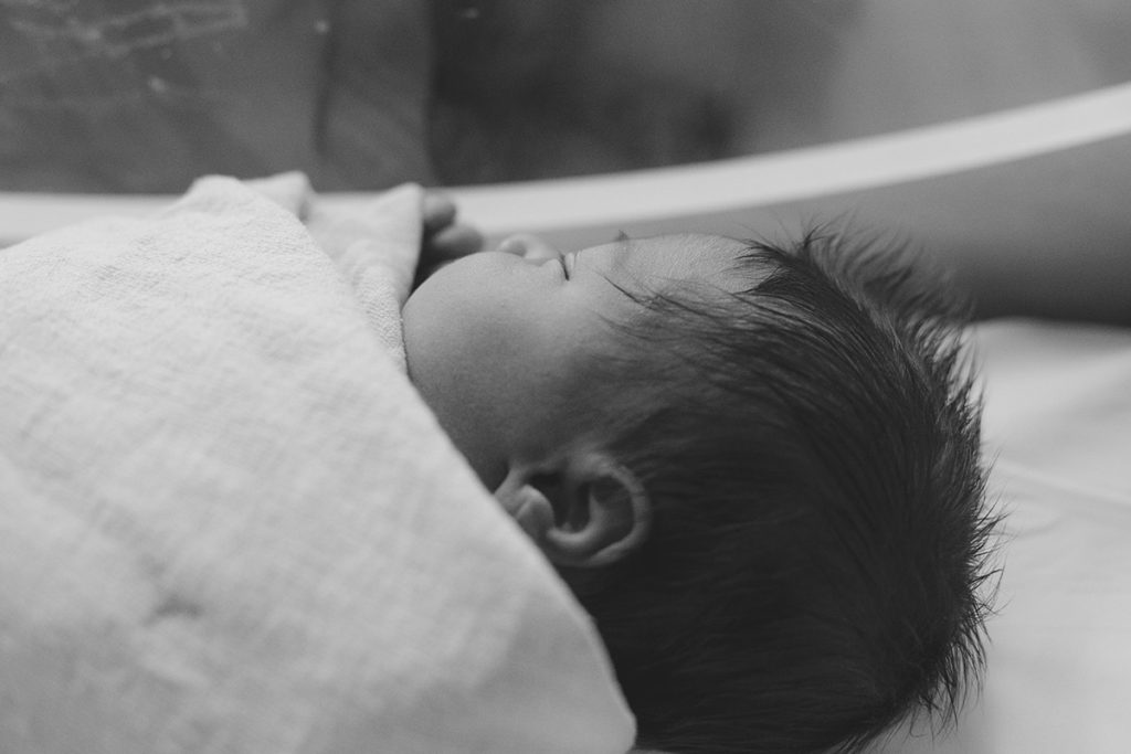 newborn boy lays in bassinet in hospital 