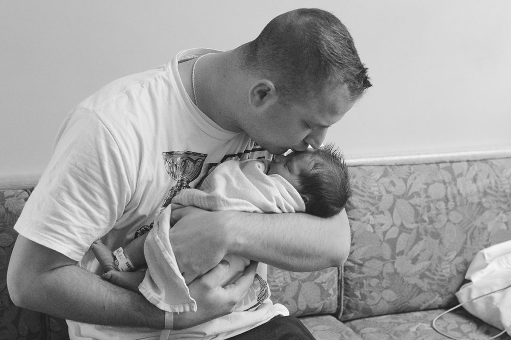 dad kisses new baby on forehead