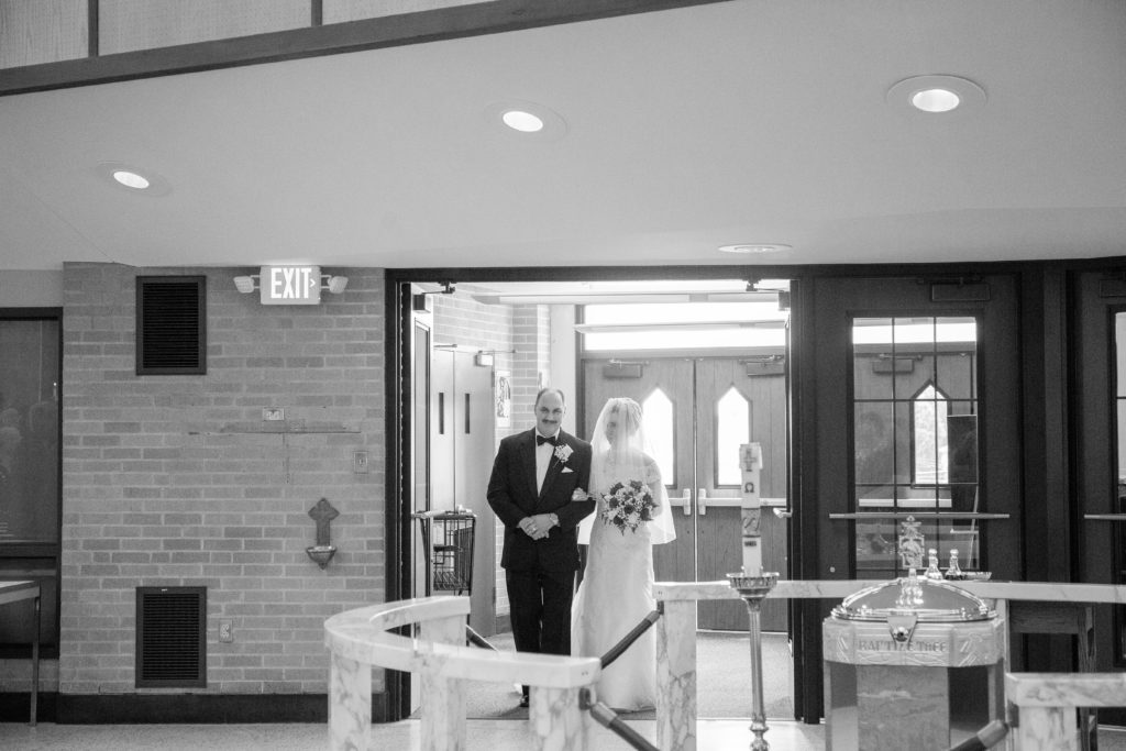 bride and father stand at doors to sanctuary before walking down the aisl