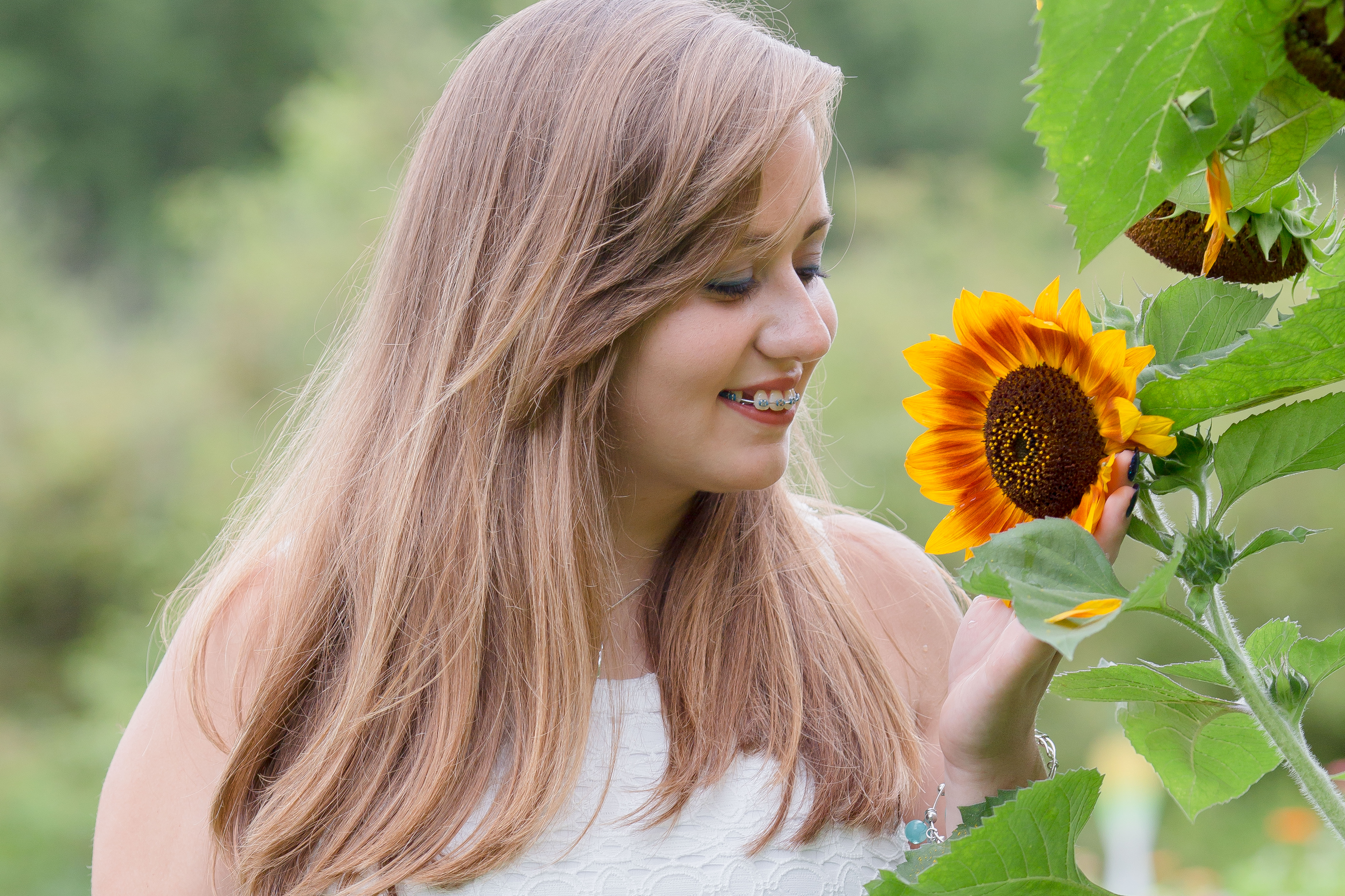 senior girl smells a sunflower in the garden