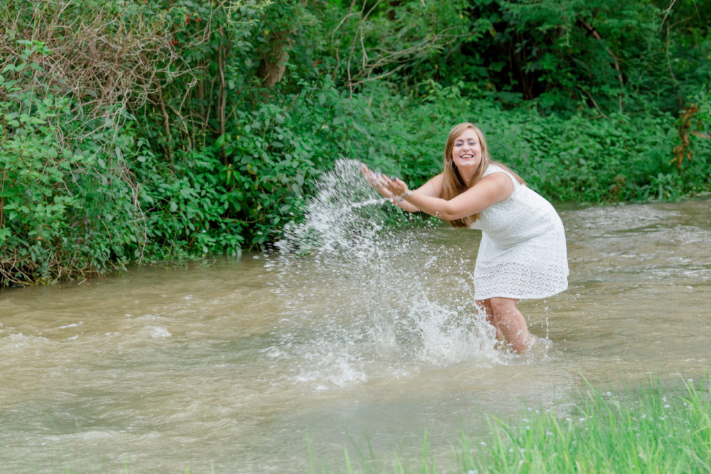 senior girl splashes in a creek in milesburg